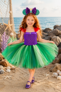 Ariel-inspired purple and green tutu dress for girls with red shoulder accents, layered green tulle skirt, jeweled bodice detail, and mermaid ear headband.