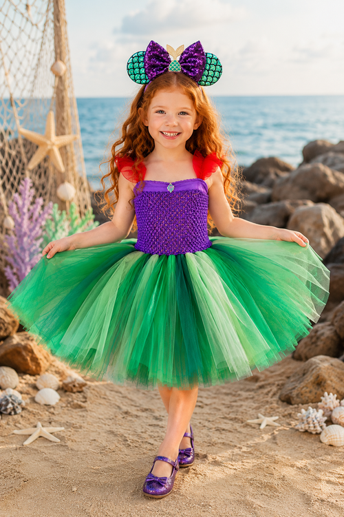 Ariel-inspired purple and green tutu dress for girls with red shoulder accents, layered green tulle skirt, jeweled bodice detail, and mermaid ear headband.