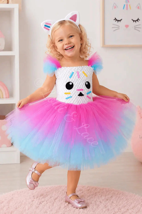 Adorable Cakey-inspired tutu dress featuring a white sprinkle-themed bodice, pink and blue layered tulle skirt, and matching kitty ear headband. Perfect for Gabby's Dollhouse themed birthdays, Halloween costumes, photoshoots, and everyday imaginative play.