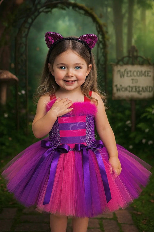 Girl wearing Cheshire's Wonderland Whimsy Tutu Dress & Accessory Set featuring a pink and purple striped tutu dress, sparkling cat ears headband, striped arm warmers, and striped socks.