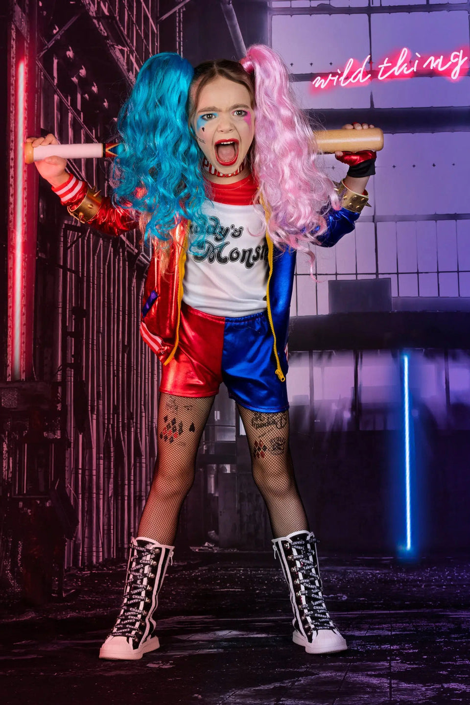 Girl's Harley Quinn costume set featuring red and blue jacket, matching shorts, two-tone wig, bat accessory, fishnet tights, and complete cosplay accessories.