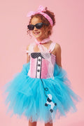 Girl wearing a pink and turquoise 1950s poodle tutu dress with a polka-dot headband, pink scarf, and black cat-eye glasses.