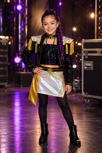 Girl wearing Rumi Demon Hunters black sequin pop star costume with holographic skirt and gold stage accessories