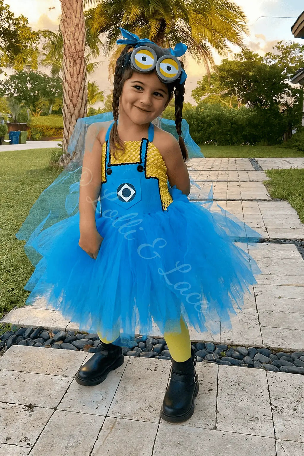 Girl wearing Minion Banana Adventure Tutu Dress and Accessory Set featuring yellow and blue tutu dress, goggles, and matching bow accessories.